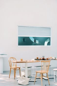 A modern cafe interior with wooden chairs and tables against a white background. Perfect for dining themes.