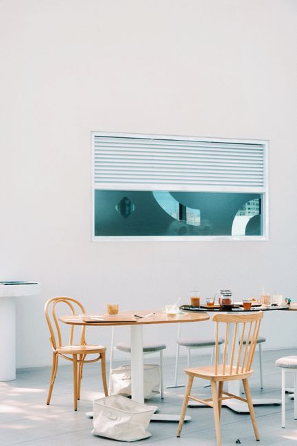 A modern cafe interior with wooden chairs and tables against a white background. Perfect for dining themes.