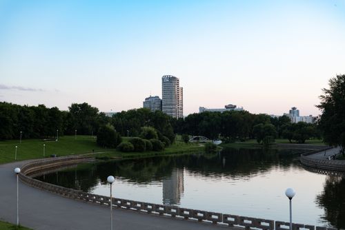 Free A peaceful urban park with a curved river and city skyline at dusk, offering scenic beauty. Stock Photo