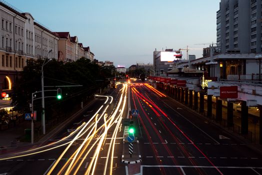 Urban street scene at dusk with dynamic light trails from traffic, showcasing city life and movement.