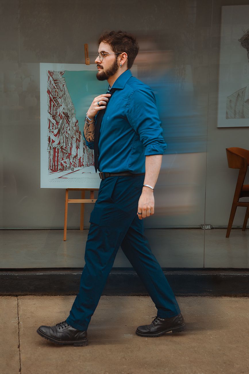 Um homem com uma camisa azul e gravata passa por uma exposição de arte em um ambiente contemporâneo.