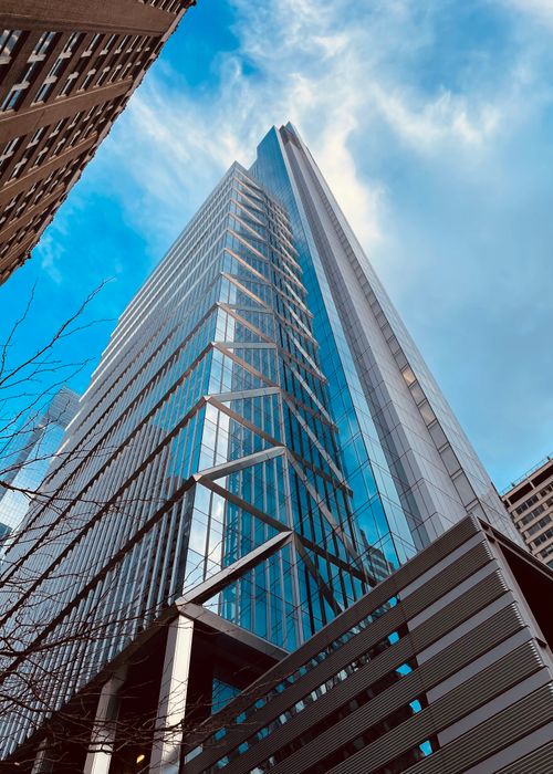 Free A modern skyscraper with a unique design reaching into a clear, blue sky. Stock Photo