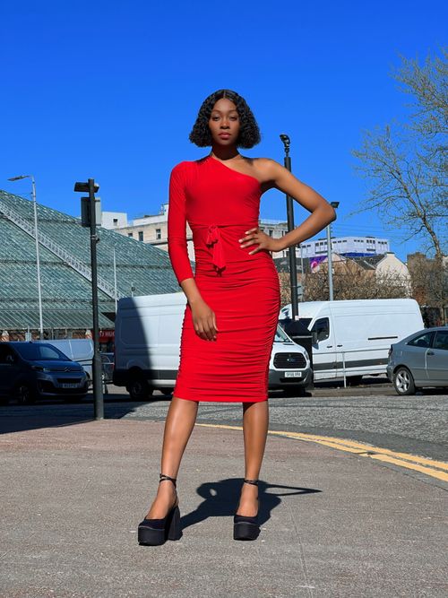 Free Fashionable woman posing in a striking red dress on a sunny street in Glasgow, Scotland. Stock Photo