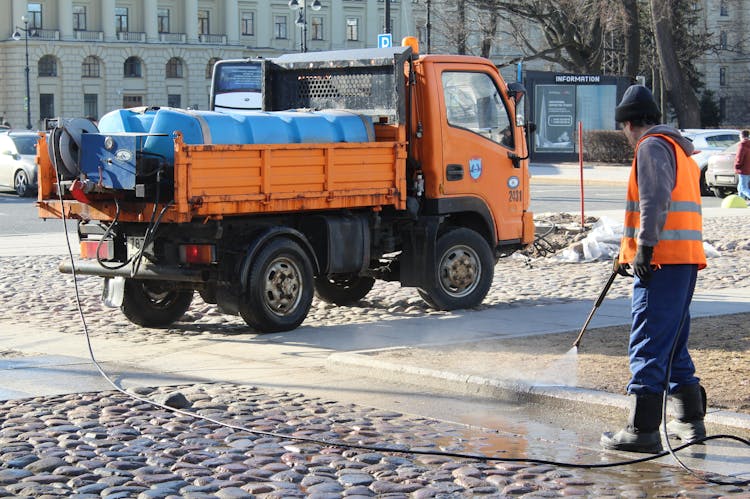 Worker Cleaning Street In City