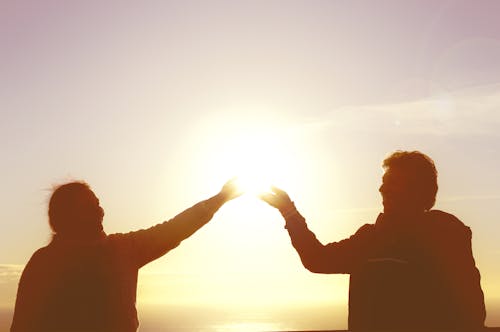 Sunlight over Smiling Couple Posing with Hands Raised