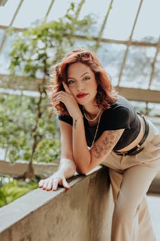 Portrait of a redhead woman with tattoos leaning indoors, showcasing modern style fashion.