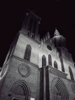 Monochrome view of a Gothic church facade in Łódź, Poland, captured at night.