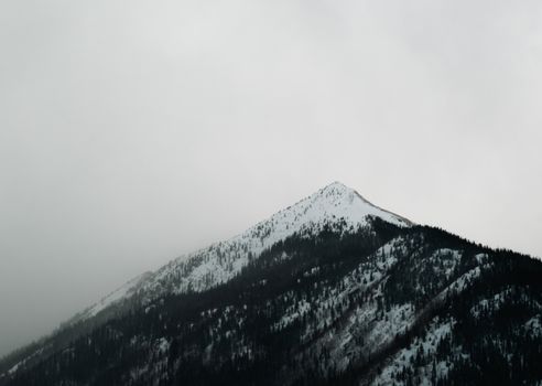 A serene snowcapped mountain under a cloudy sky, capturing the essence of winter tranquility.