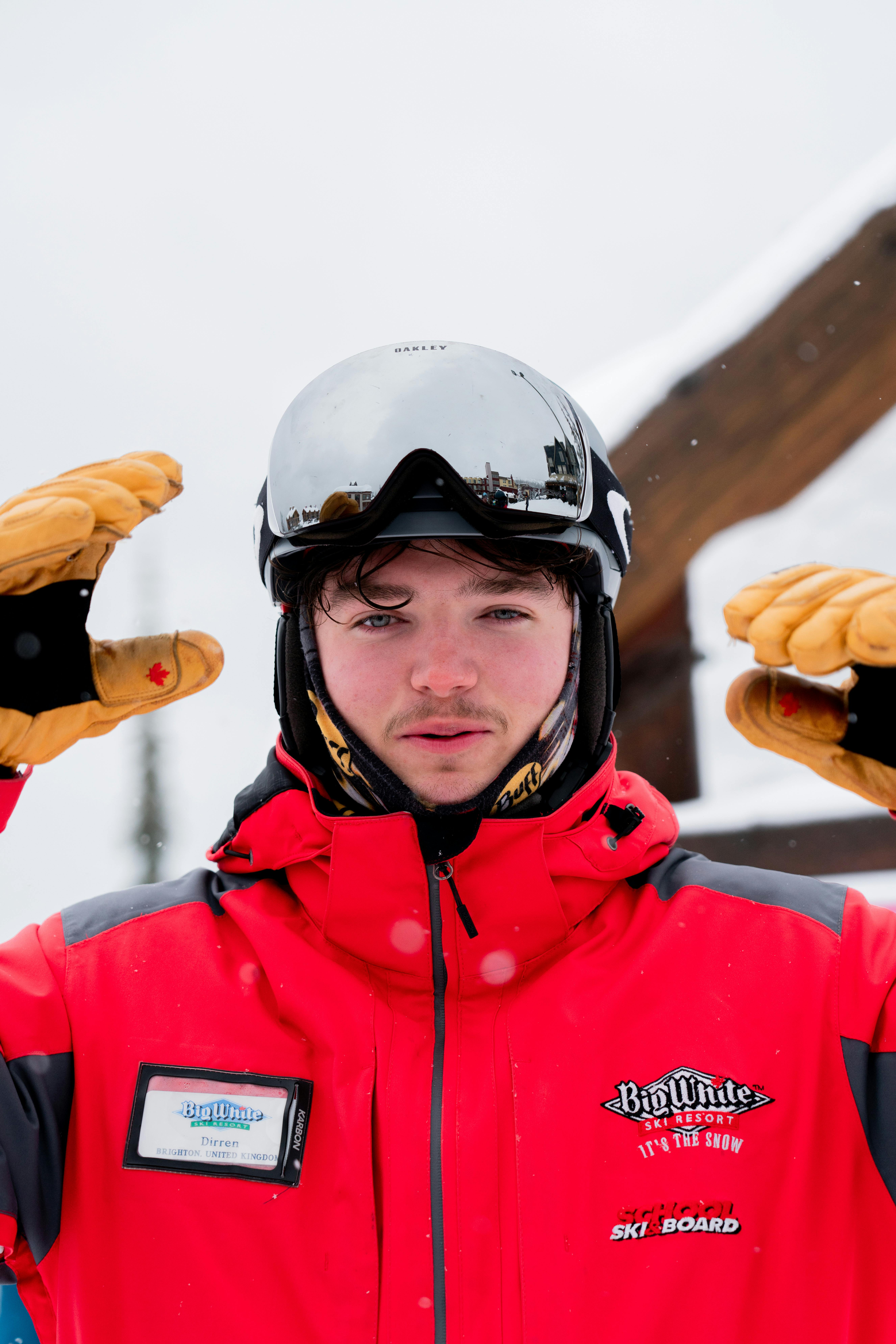 Prescription Goggle Inserts - Portrait of a young skier wearing goggles and a red jacket at a snowy ski resort.