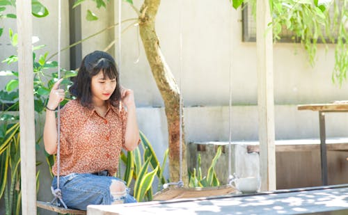 Woman Seated on Swing Near Tree