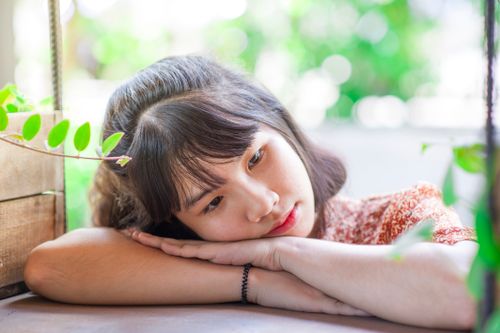 Free Close-up outdoor portrait of a thoughtful teenager resting on a table surrounded by leaves. Stock Photo