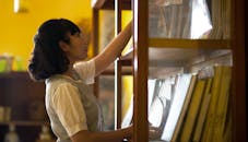 Photo of a Young Woman Reaching For Book