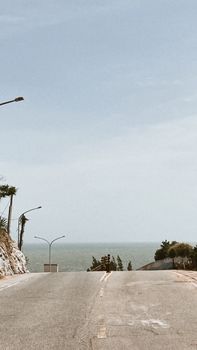 Tranquil coastal road leading to the ocean under a bright blue sky, perfect for travel inspiration.