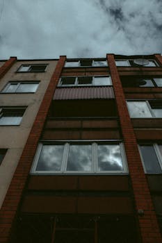 A low angle shot of an urban apartment building with cloud reflection in windows.