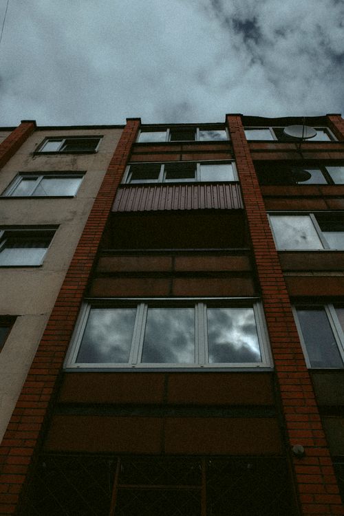 Free A low angle shot of an urban apartment building with cloud reflection in windows. Stock Photo
