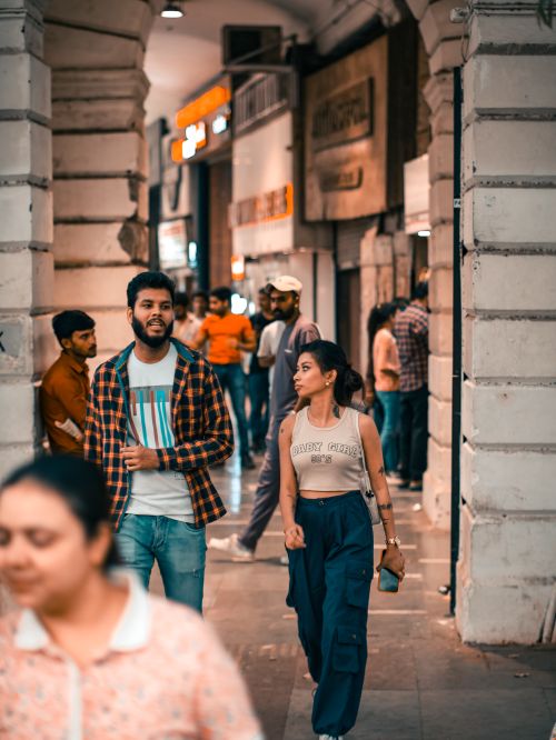 Free People walking through a busy urban corridor with vibrant shops and columns, capturing city life. Stock Photo