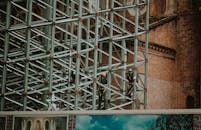 建筑工人站在现代建筑的脚手架上，展示着城市建设的风貌