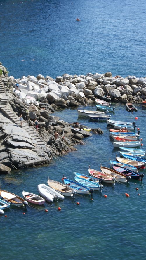 Free Aerial view of vibrant boats moored at a rocky shoreline on a sunny day. Stock Photo