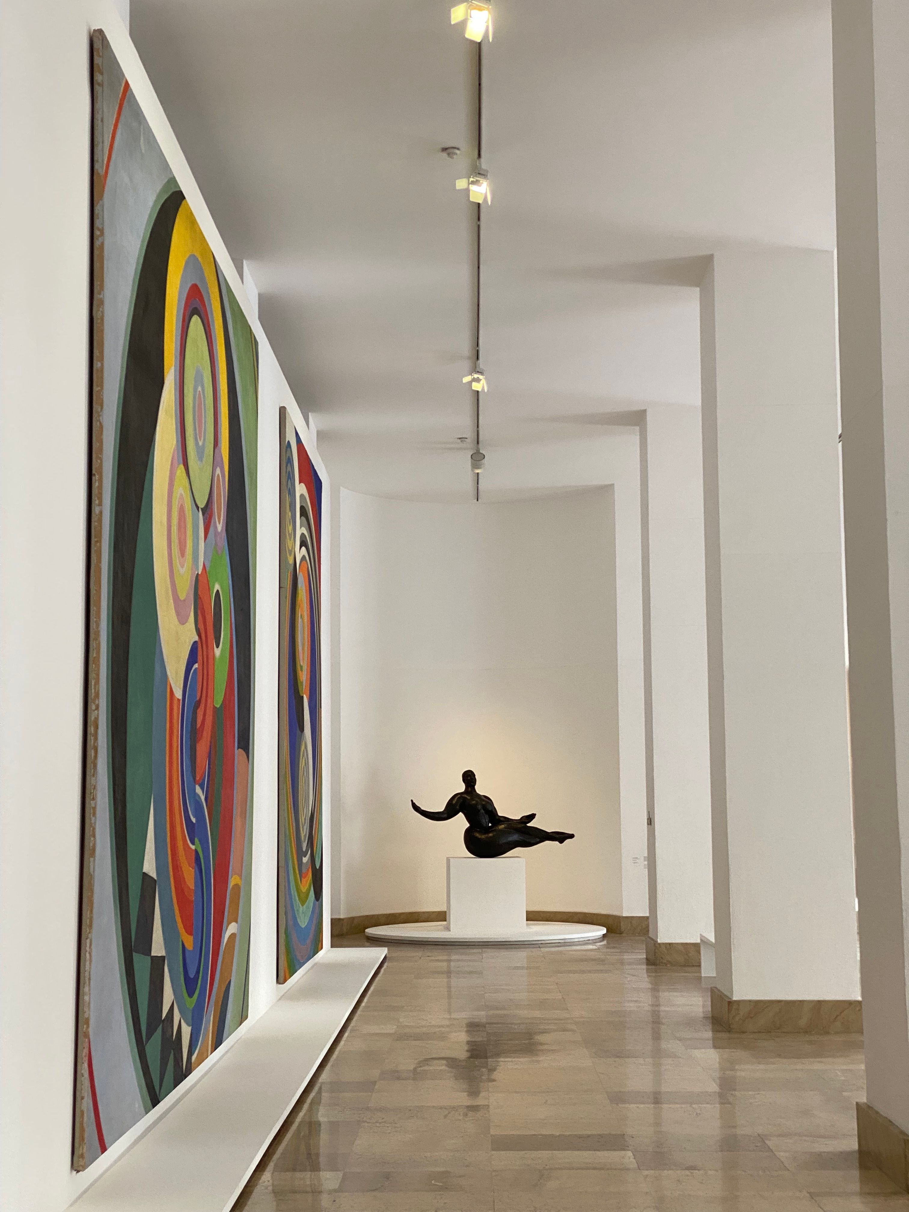 Free Elegant interior of a modern art museum in Paris showcasing abstract paintings and a sculpture. Stock Photo