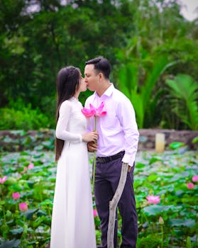 一对情侣在户外花园充满活力的莲花丛中深情接吻