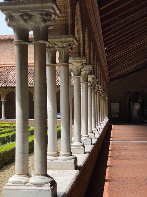 Free Ornate medieval cloister columns casting shadows in a historic courtyard. Stock Photo