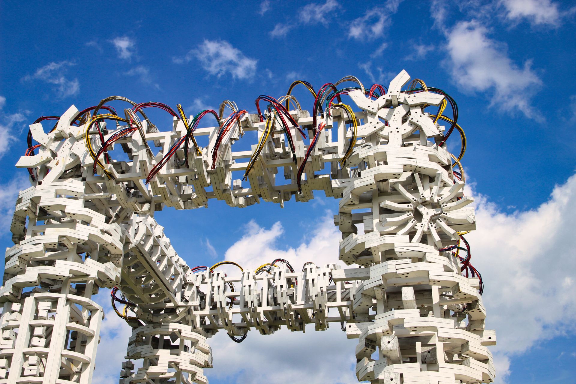 A complex white architectural structure with colorful cables beneath a clear blue sky, showcasing modern design.