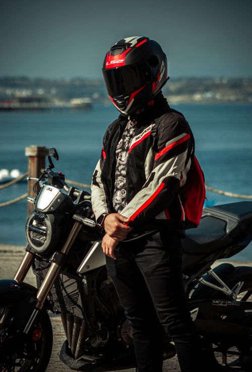 Free Biker standing near his motorcycle by the sea in Adana, Türkiye on a sunny day. Stock Photo