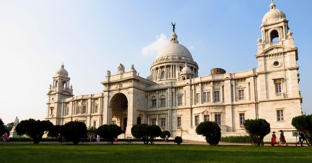 Kolkata Victoria Memorial and gardens at sunset with Bengali families on the lawn and storm clouds forming