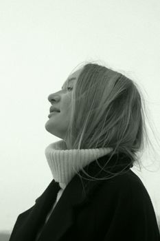 Profile of a young woman in a stylish coat and turtleneck, showcasing modern fashion.