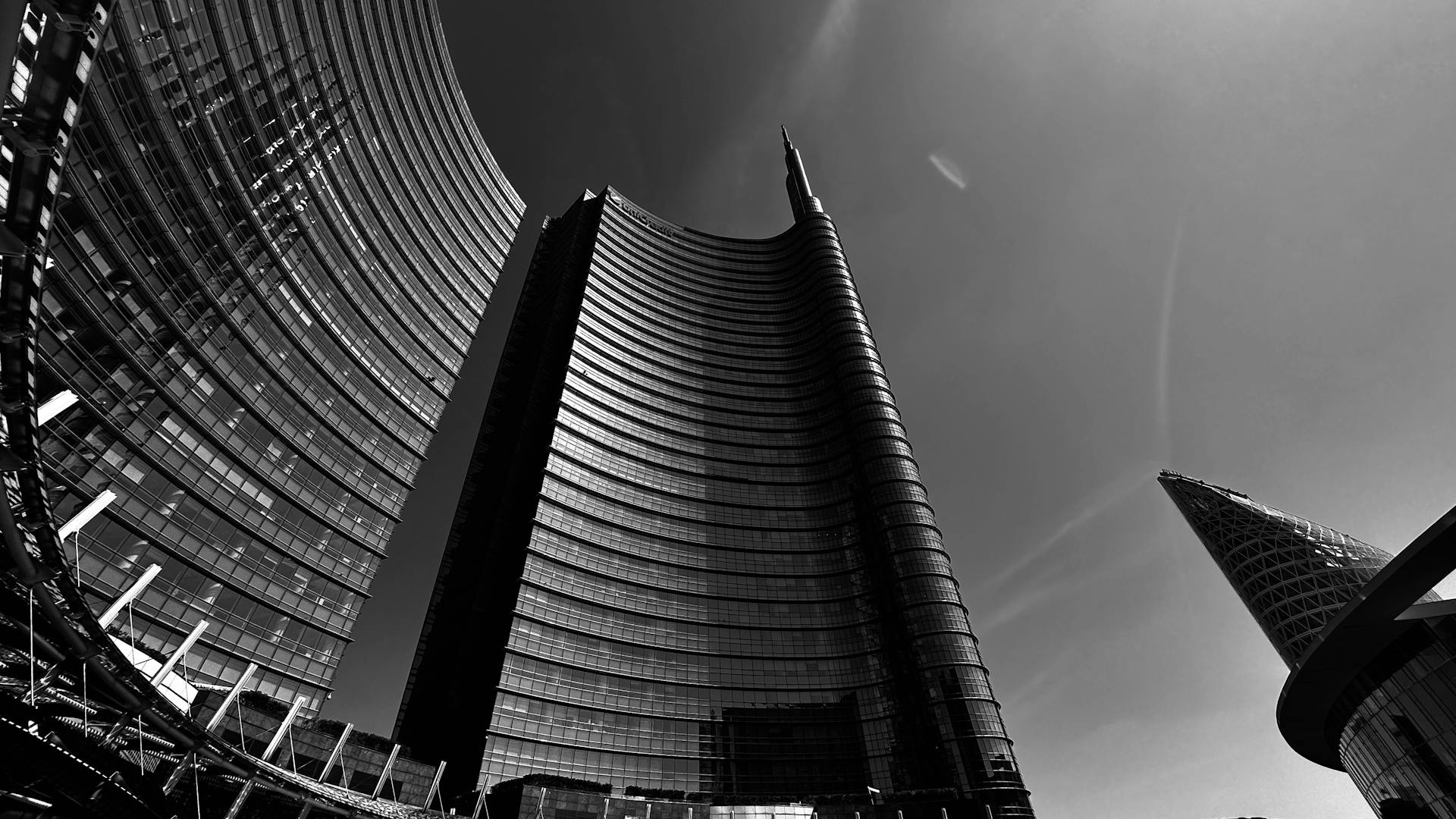 Low-angle black and white shot of the iconic UniCredit Tower in Milan, Italy, emphasizing its modern architecture.