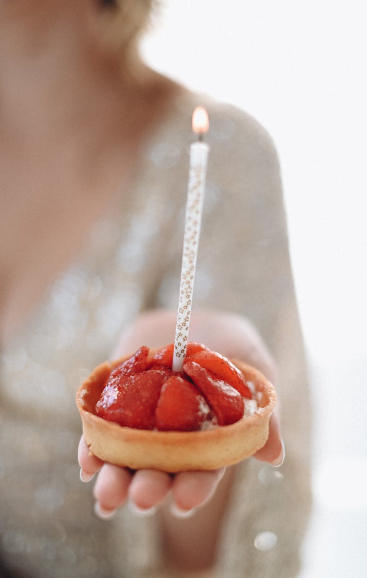 Hand Of A Woman Holding A Small Strawberry Cake With A Burning Candle