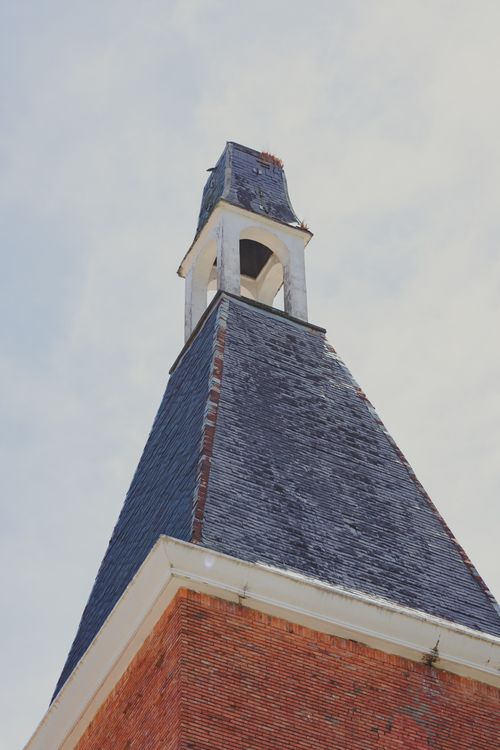 Free Low angle view of a brick tower with slate roof against a clear sky. Stock Photo