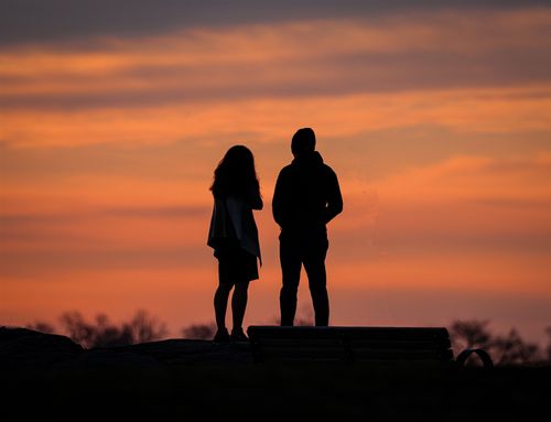 Free Silhouetted couple watching an orange sunset in Stamford, creating a serene and picturesque scene. Stock Photo