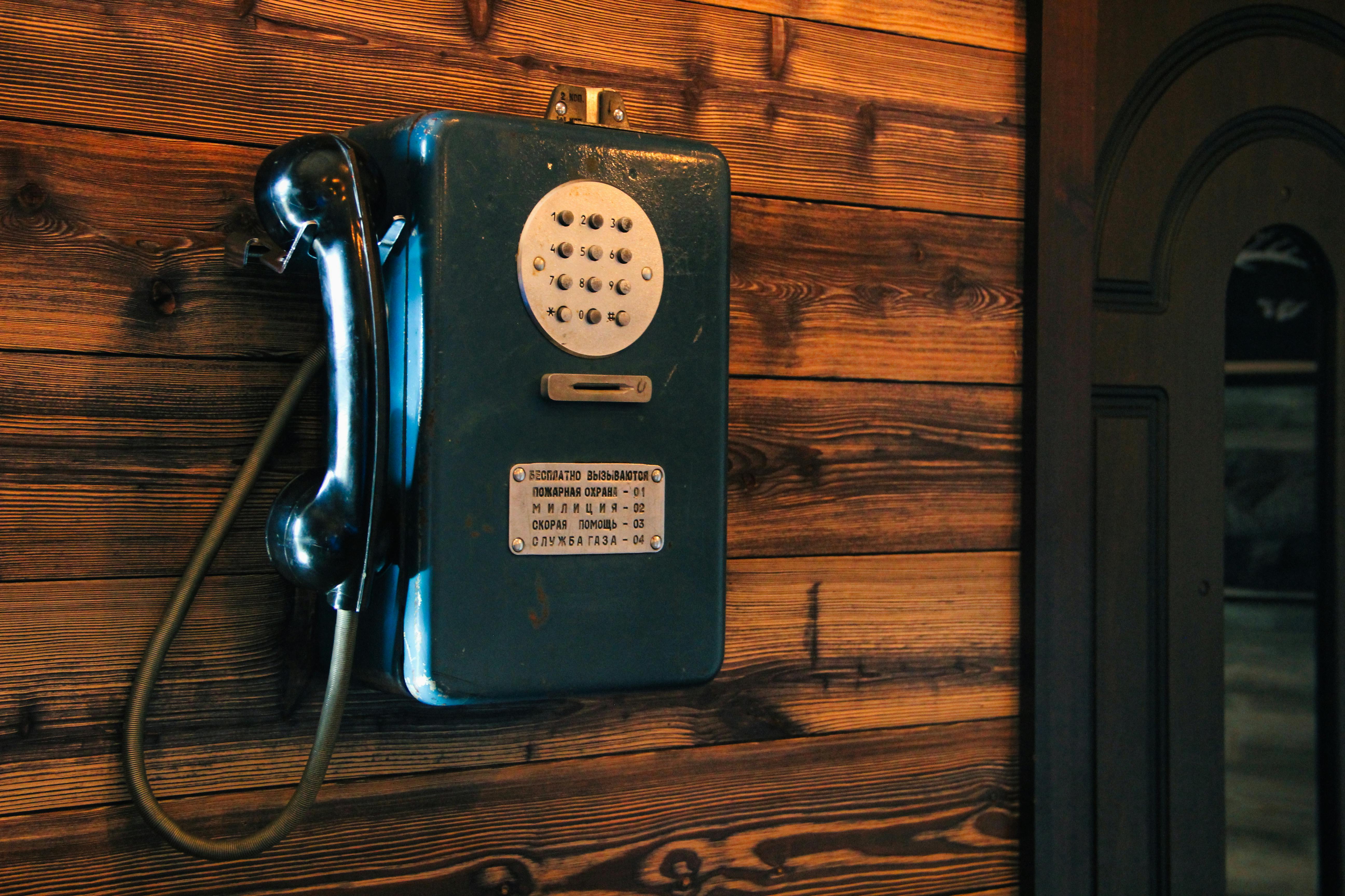 a blue telephone on a wooden wall