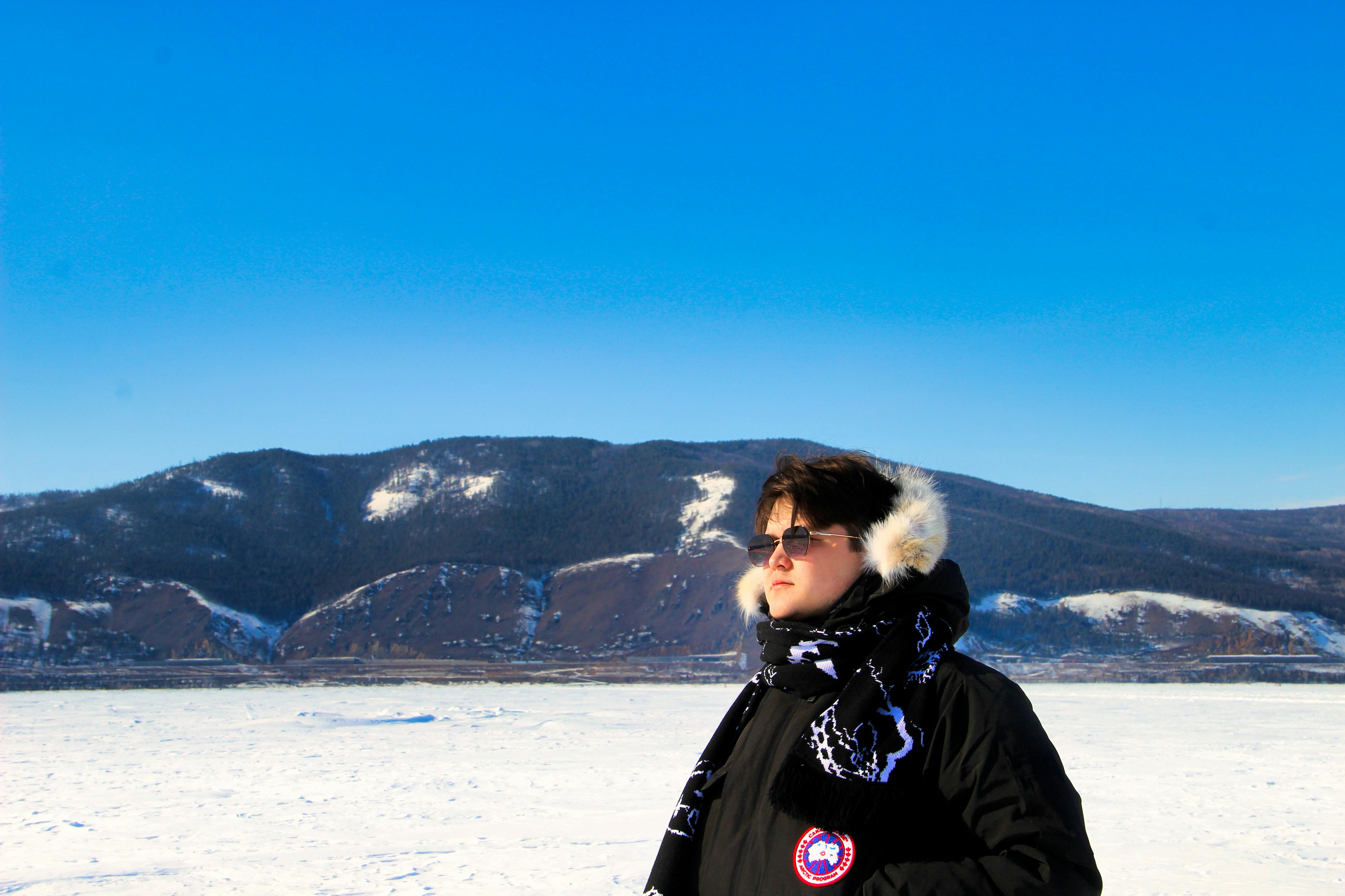 a woman in a winter coat standing on a frozen lake