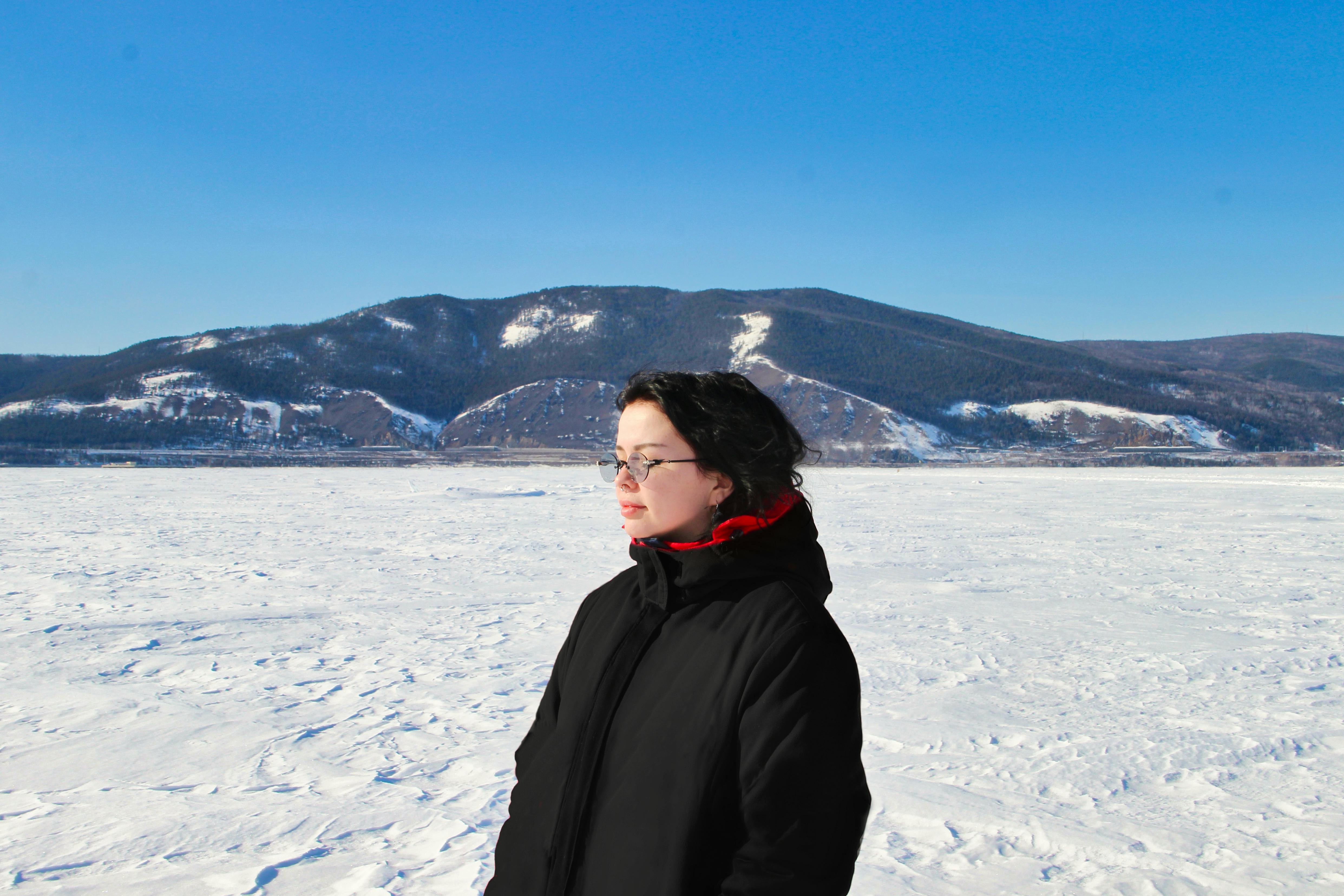 a woman standing on a frozen lake with mountains in the background