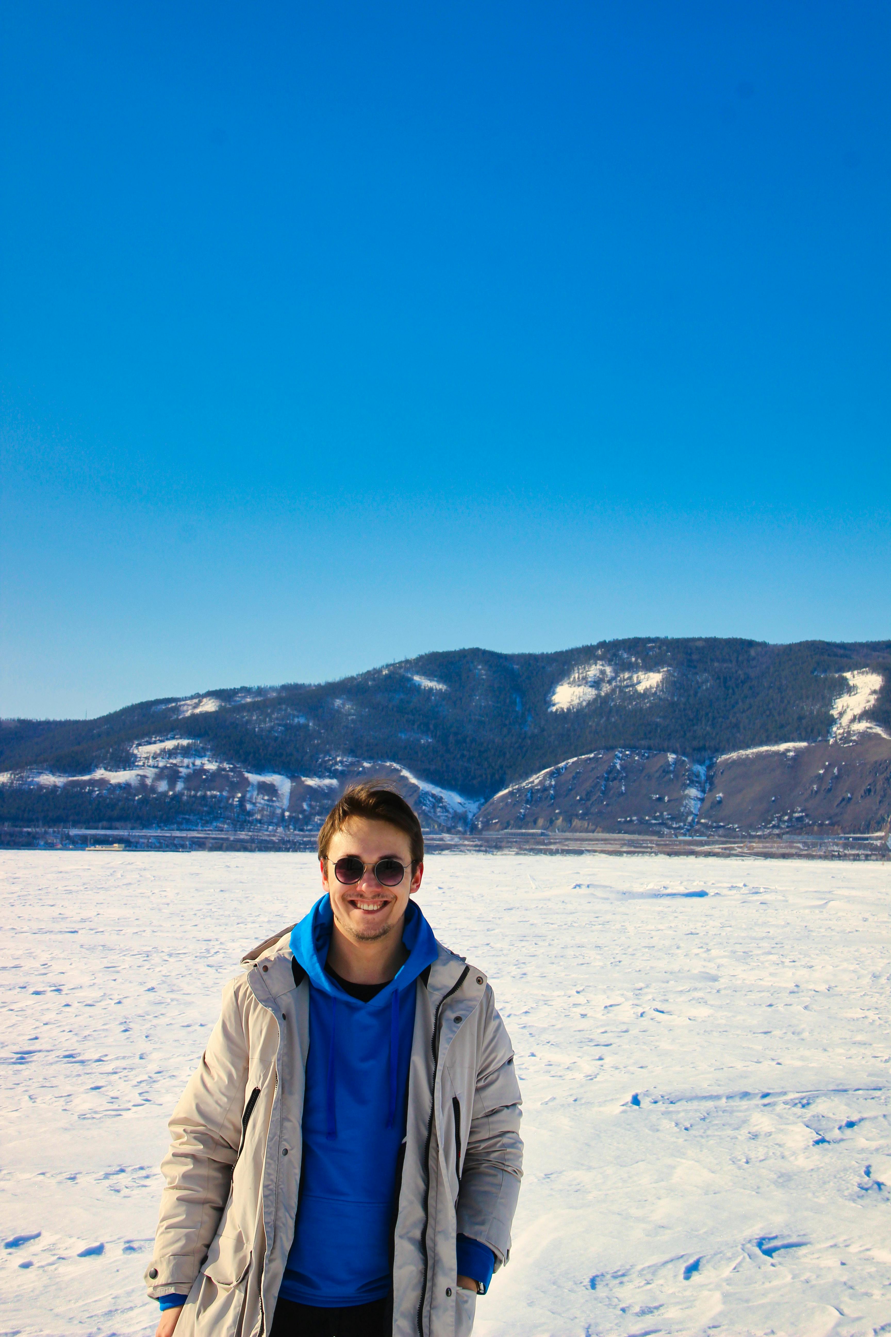 a man standing on a frozen lake with mountains in the background