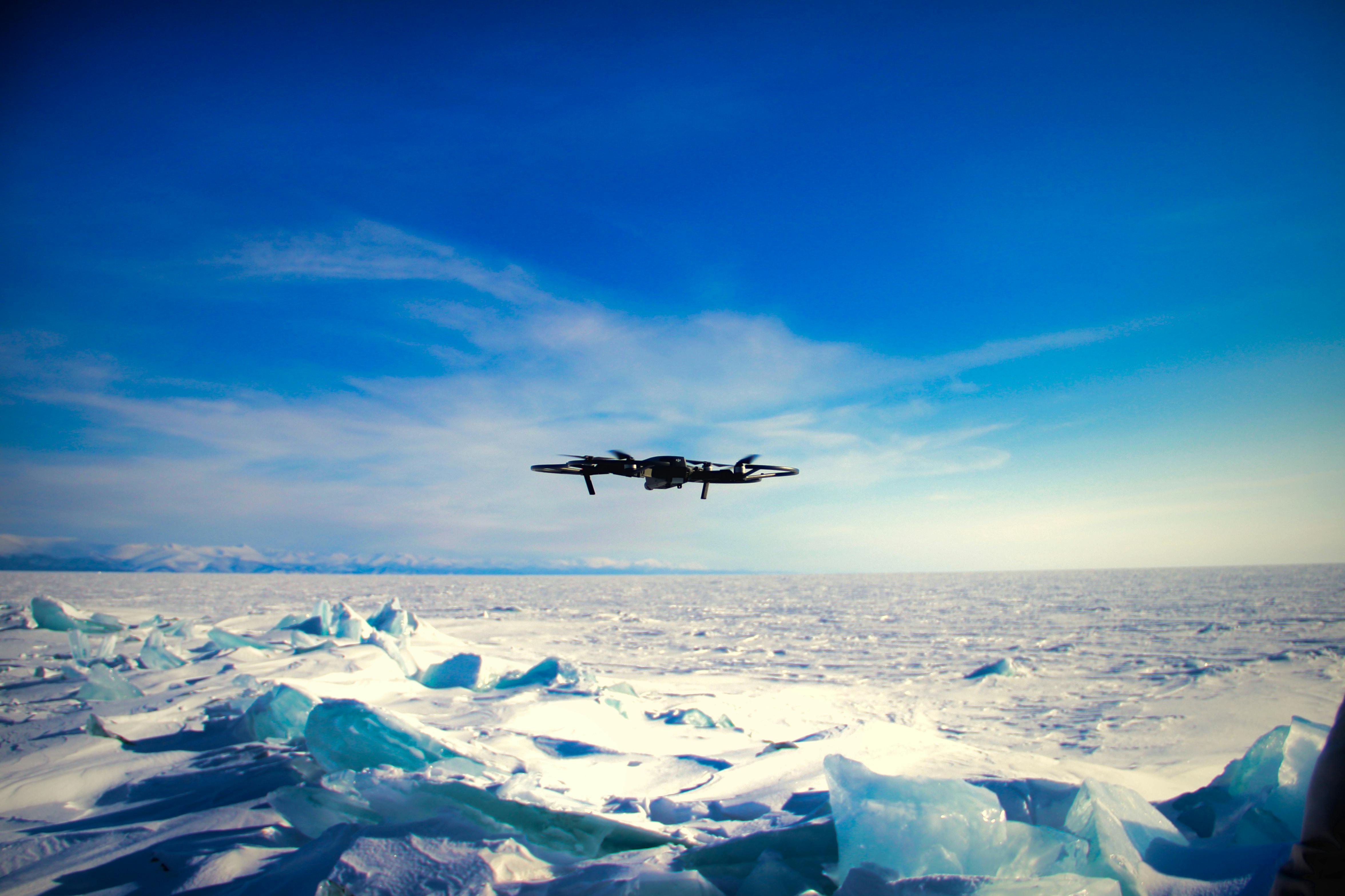 a plane flying over the ice with a blue sky