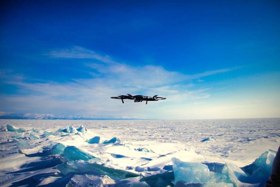 Bear Glacier Signature Helicopter Tour - Drone navigating over a vast, icy landscape under a clear blue sky, showcasing adventurous exploration.