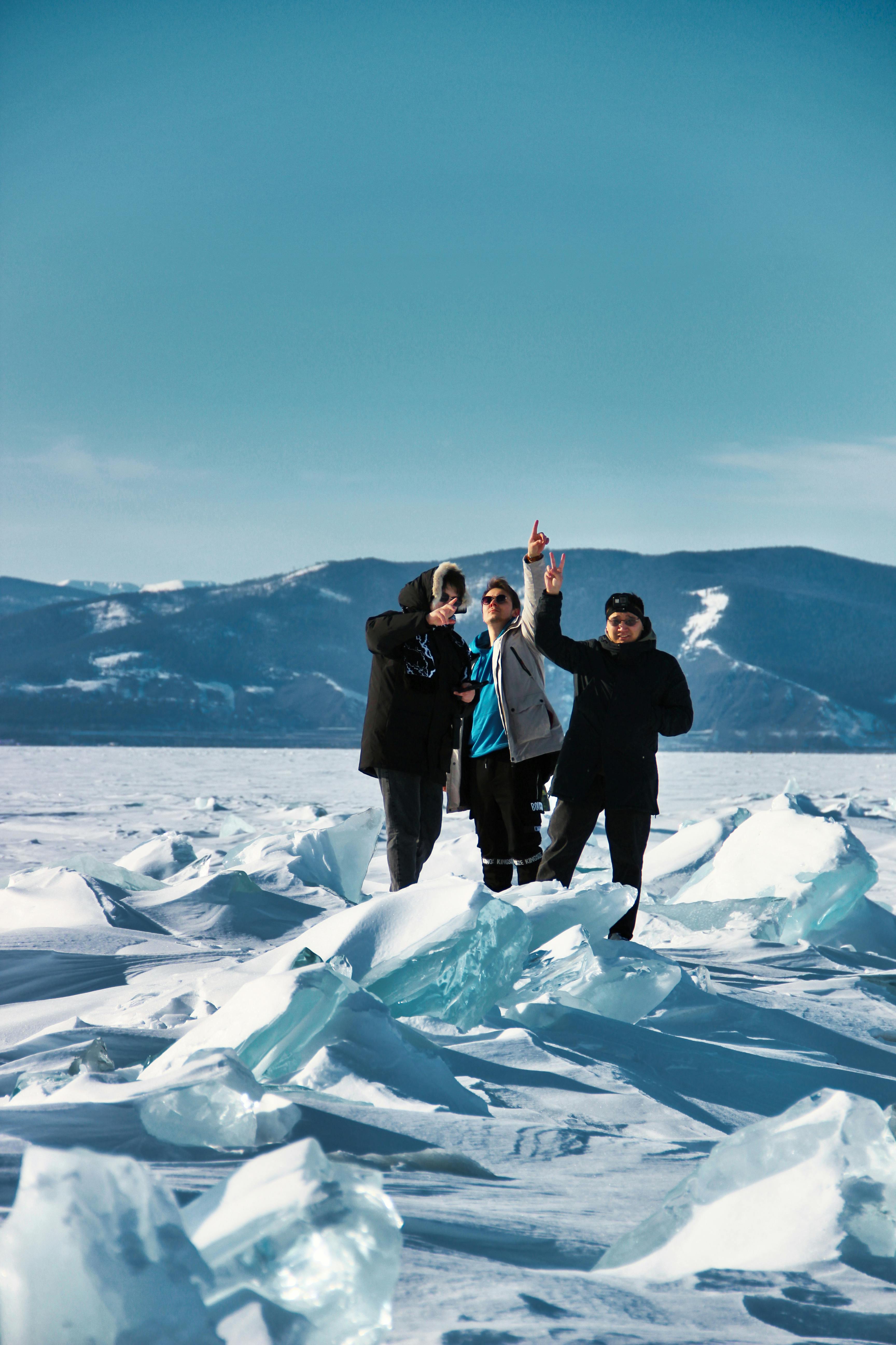 three people standing on top of ice with their arms up