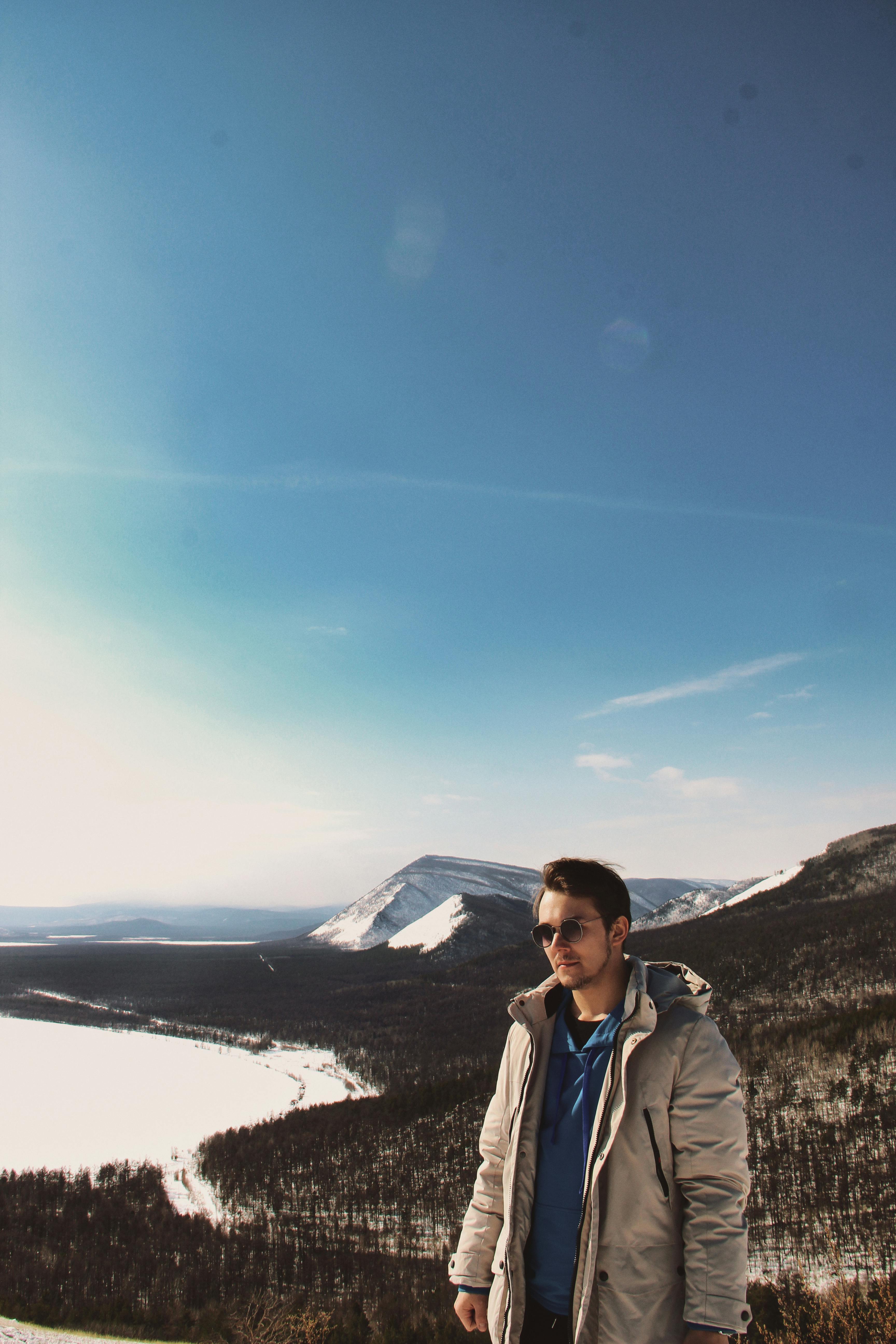 a man standing on a hill with a mountain in the background