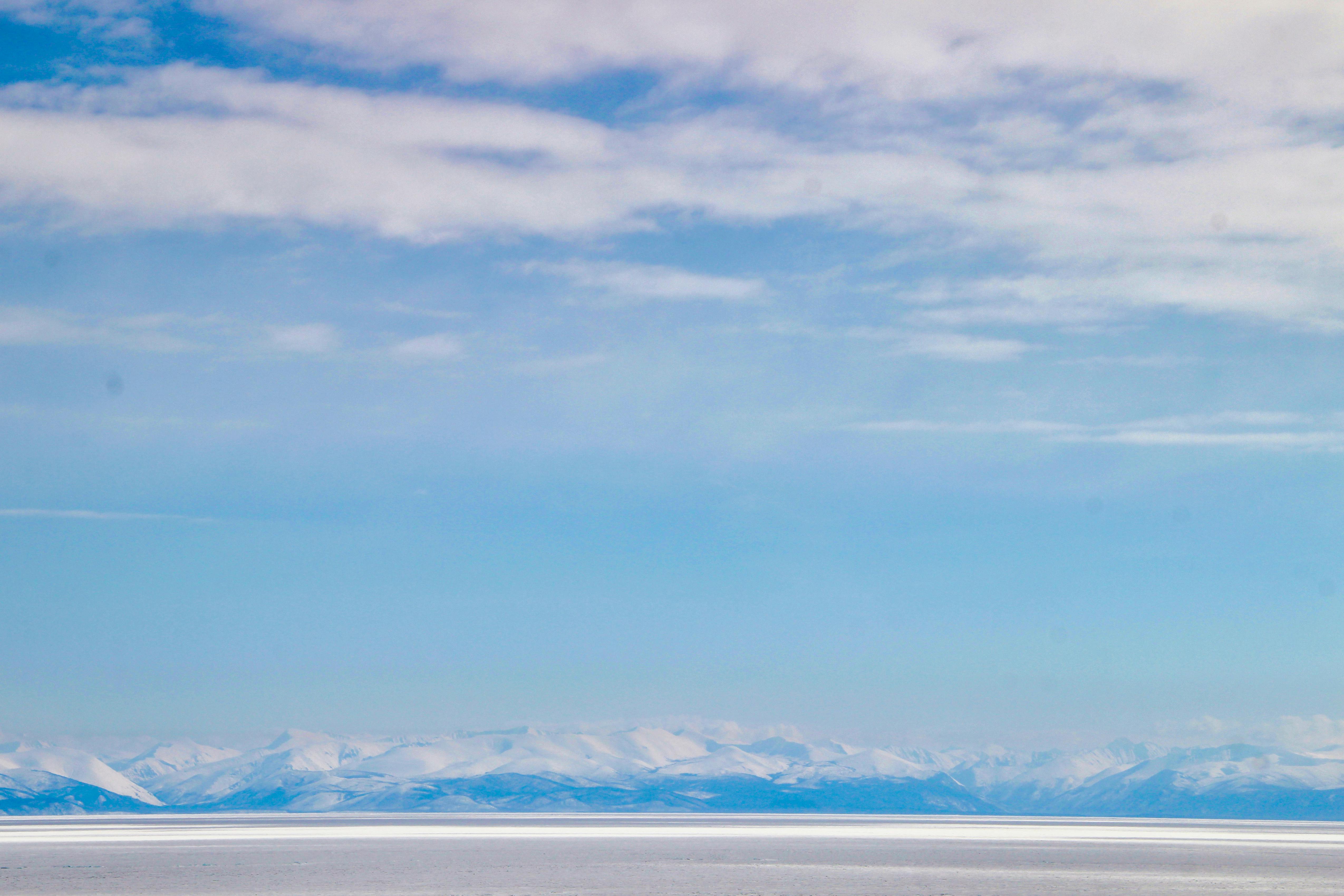 a person standing on a snow covered beach with mountains in the background