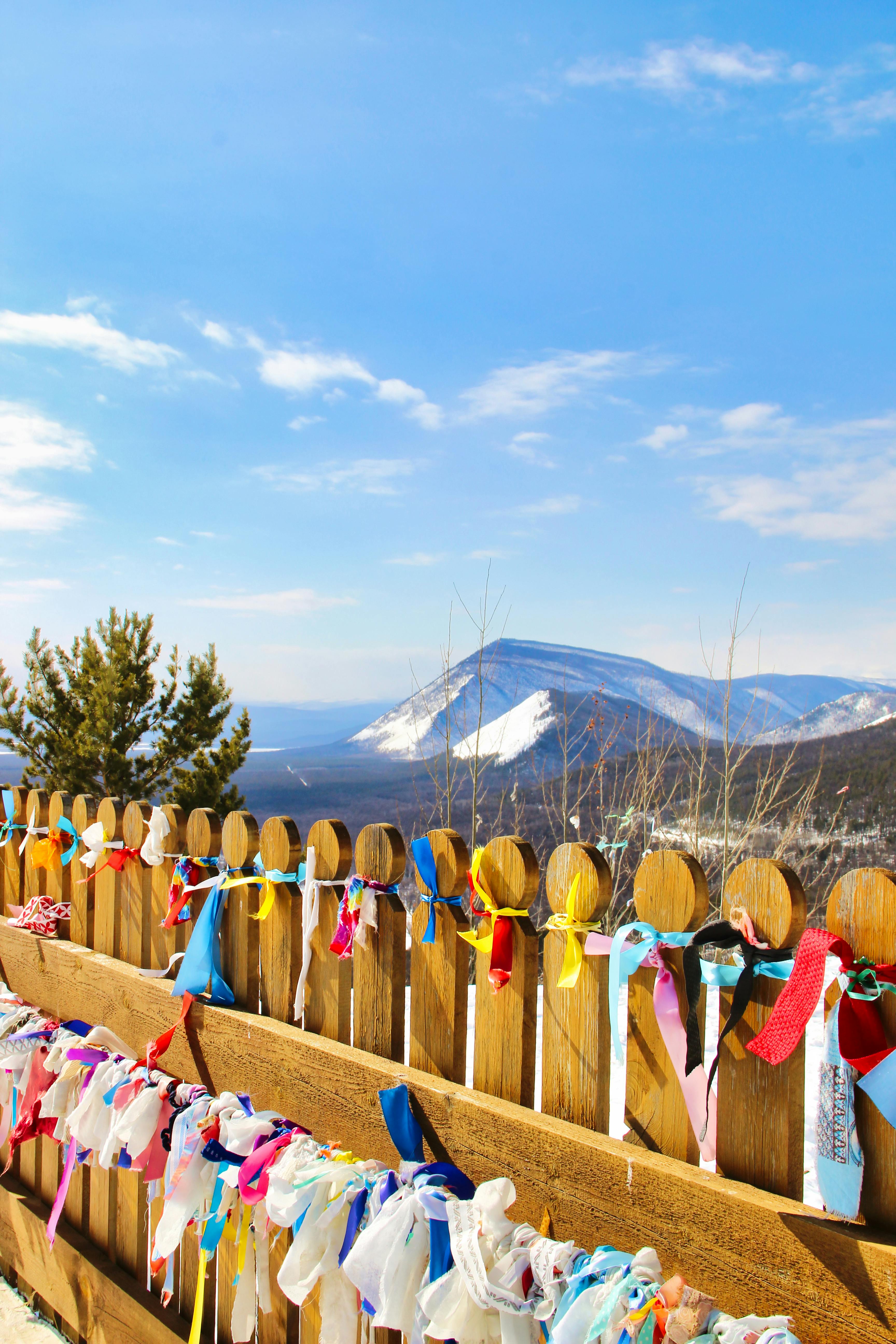 a wooden fence with colorful ribbons tied to it