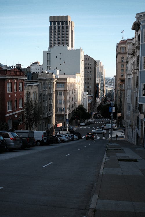 View of a Street between Residential Buildings and Cars Parked on the Sides 