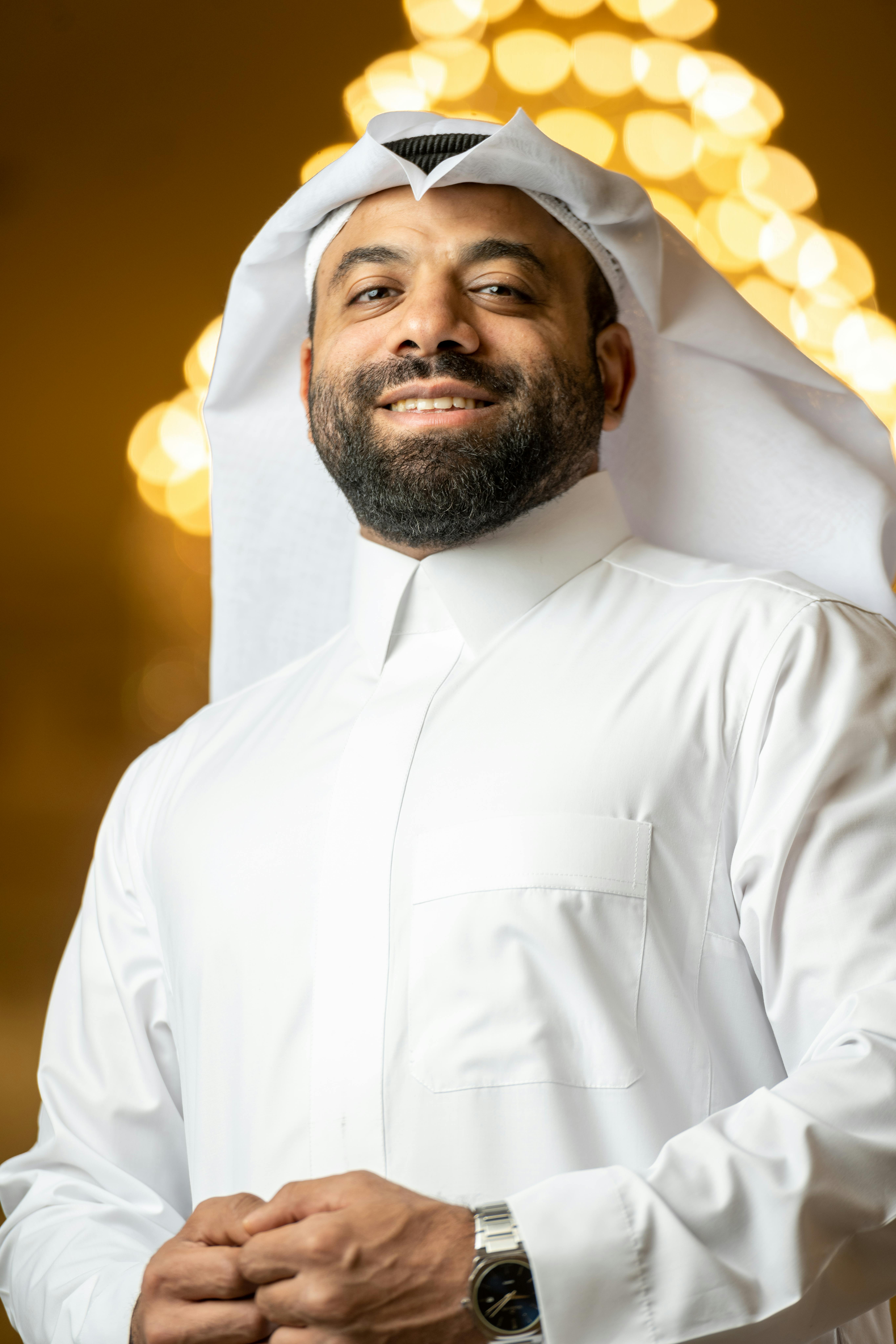 Portrait of a smiling Middle Eastern man wearing a keffiyeh and white attire, exuding confidence.