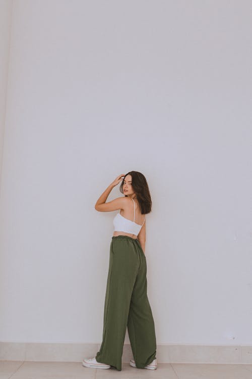 Studio Shot of a Young Woman in a White Crop Top and Khaki Trousers Looking over Her Shoulder
