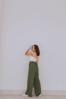 Young woman posing in casual fashion against a minimalist white wall.