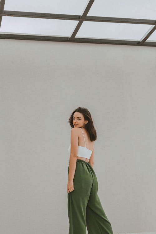 Studio Shot of a Young Woman in a White Crop Top and Khaki Trousers Looking over Her Shoulder