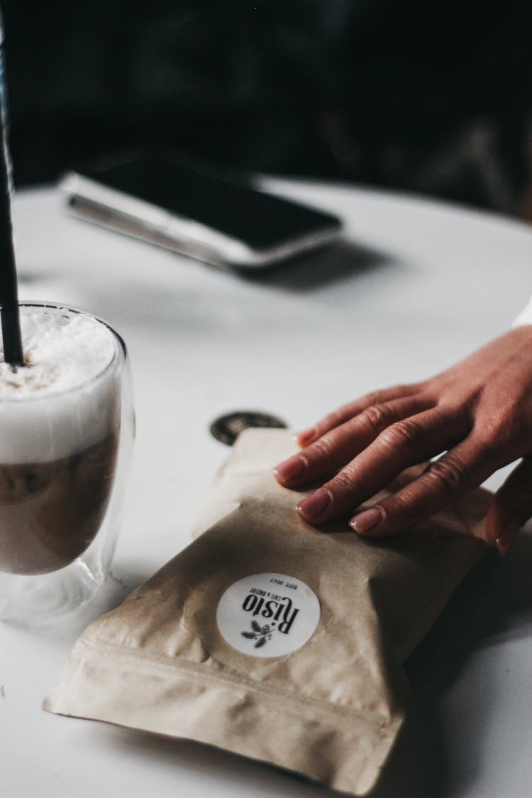 Woman Hand Near Coffee Bag And Drink On Table