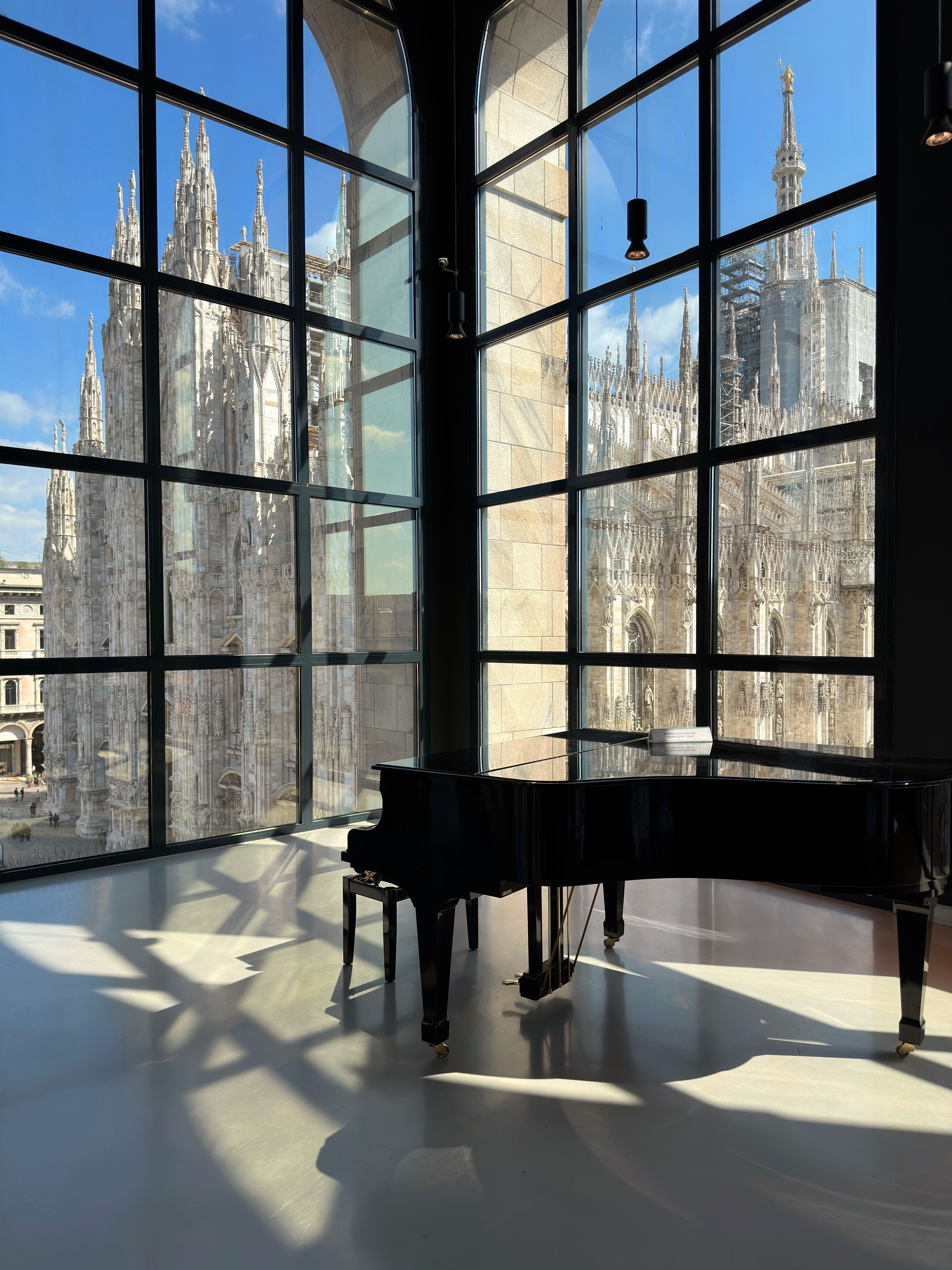 Elegant grand piano by large window with view of Milan Cathedral, Italy.